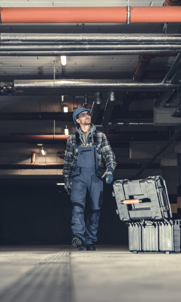 Plumbing,Technician,Walking,Along,Underground,Parking,With,His,Tools,Box